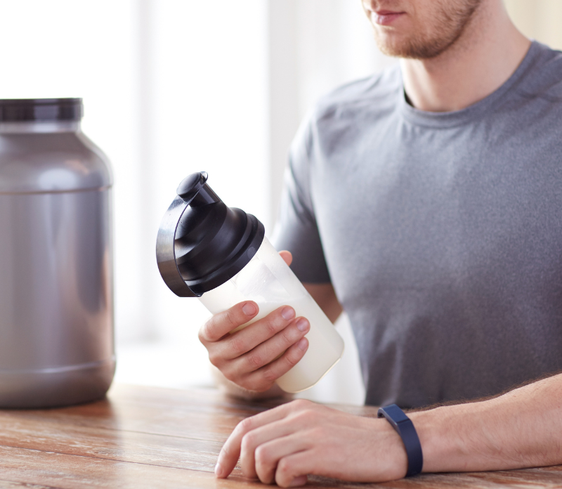 young athlete taking creatine supplement in shaker cup