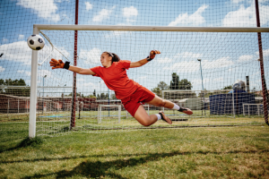 young female soccer goalkeeper diving for ball