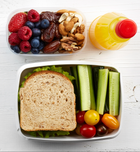 lunch containers with sandwich, fruit, nuts, juice bottle