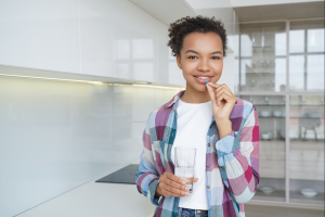 teen girl taking a vitamin supplement with water